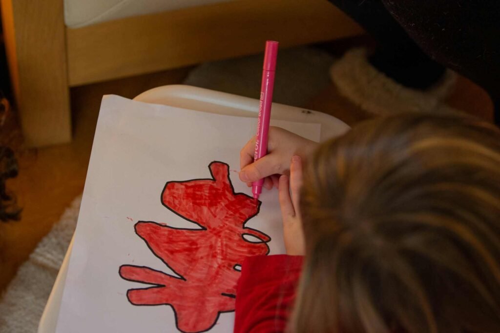 A child drawing with a red water based marker.