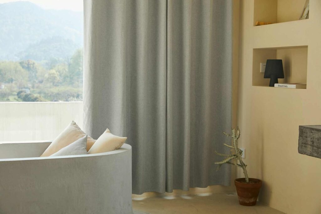 Thick grey curtains in front of a window in a room.